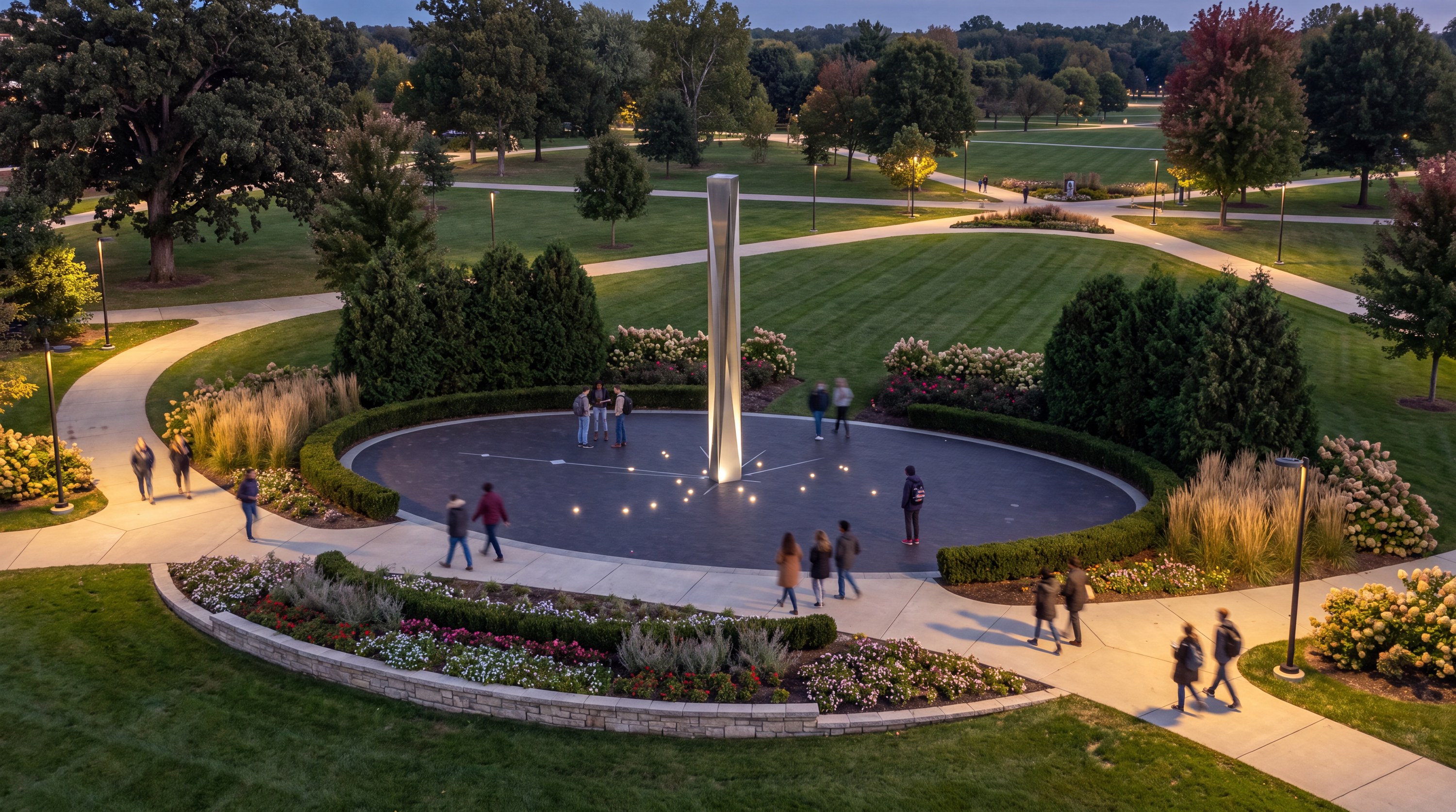 Illuminated obelisk on a circular plaza in a campus park